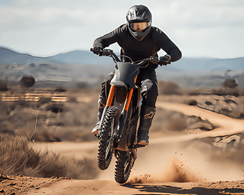 Cemotoride electric dirt bike with gold suspension performing a wheelie on a desert trail.