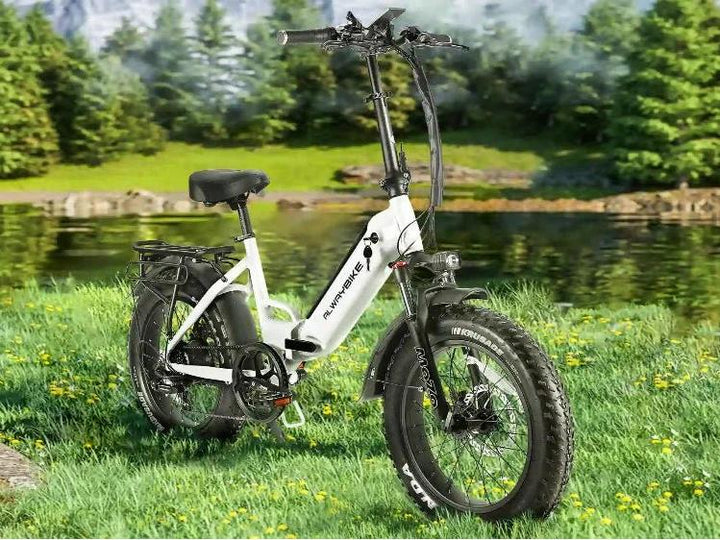 White CEMOTO step-through folding electric bike with fat tires parked on grass near a lake in a forest